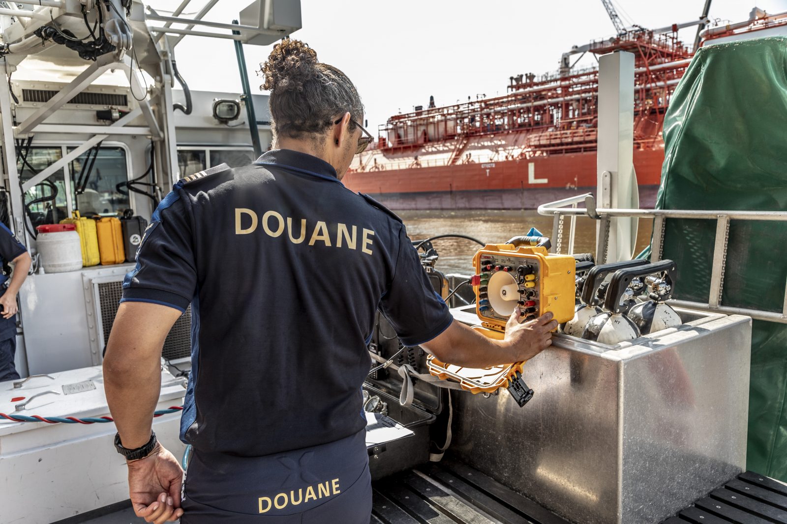 Een douanier die op een schip apparatuur checkt om met de duiker te communiceren. 