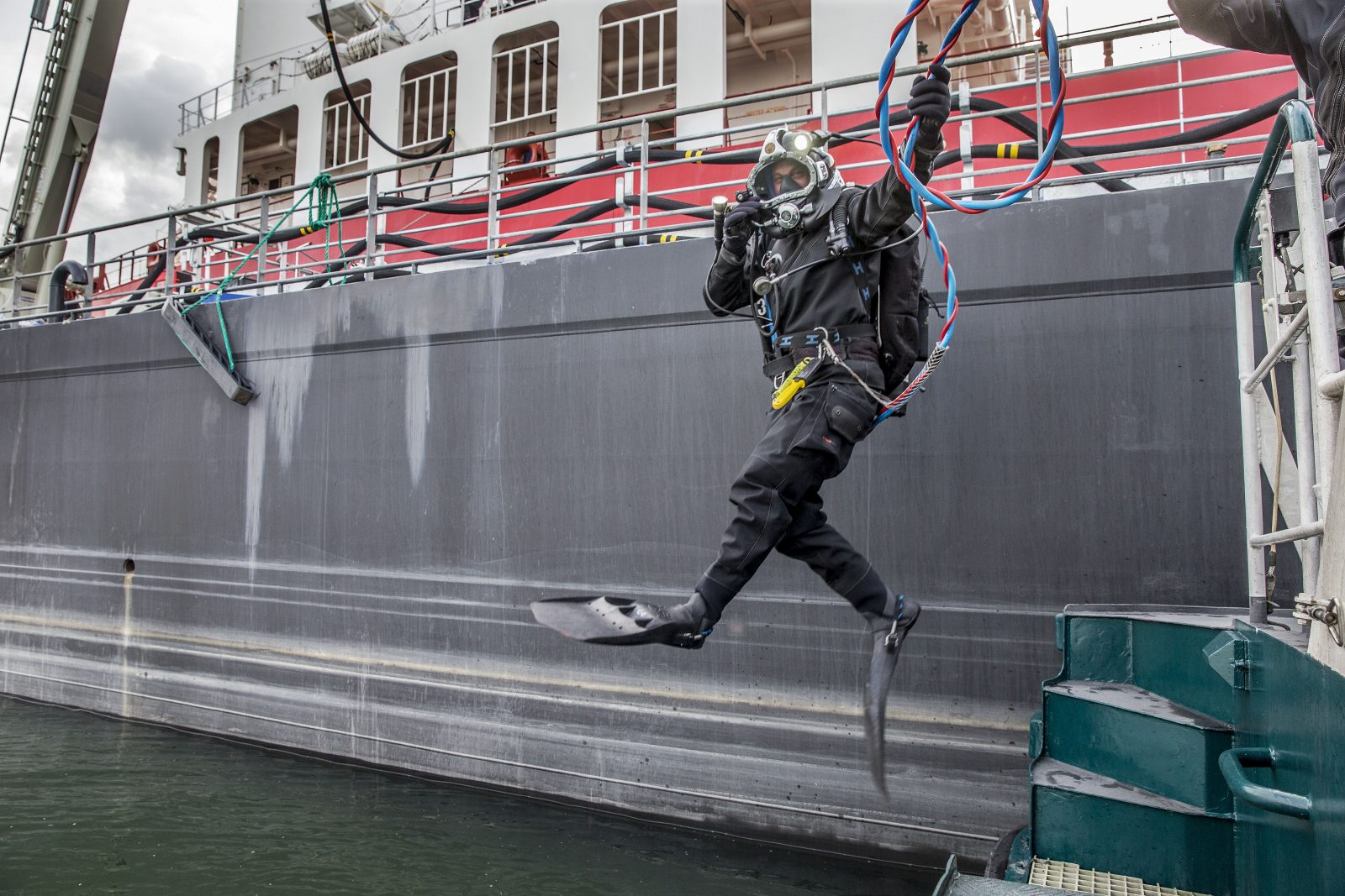 Een duiker springt vanaf een schip in het water. 