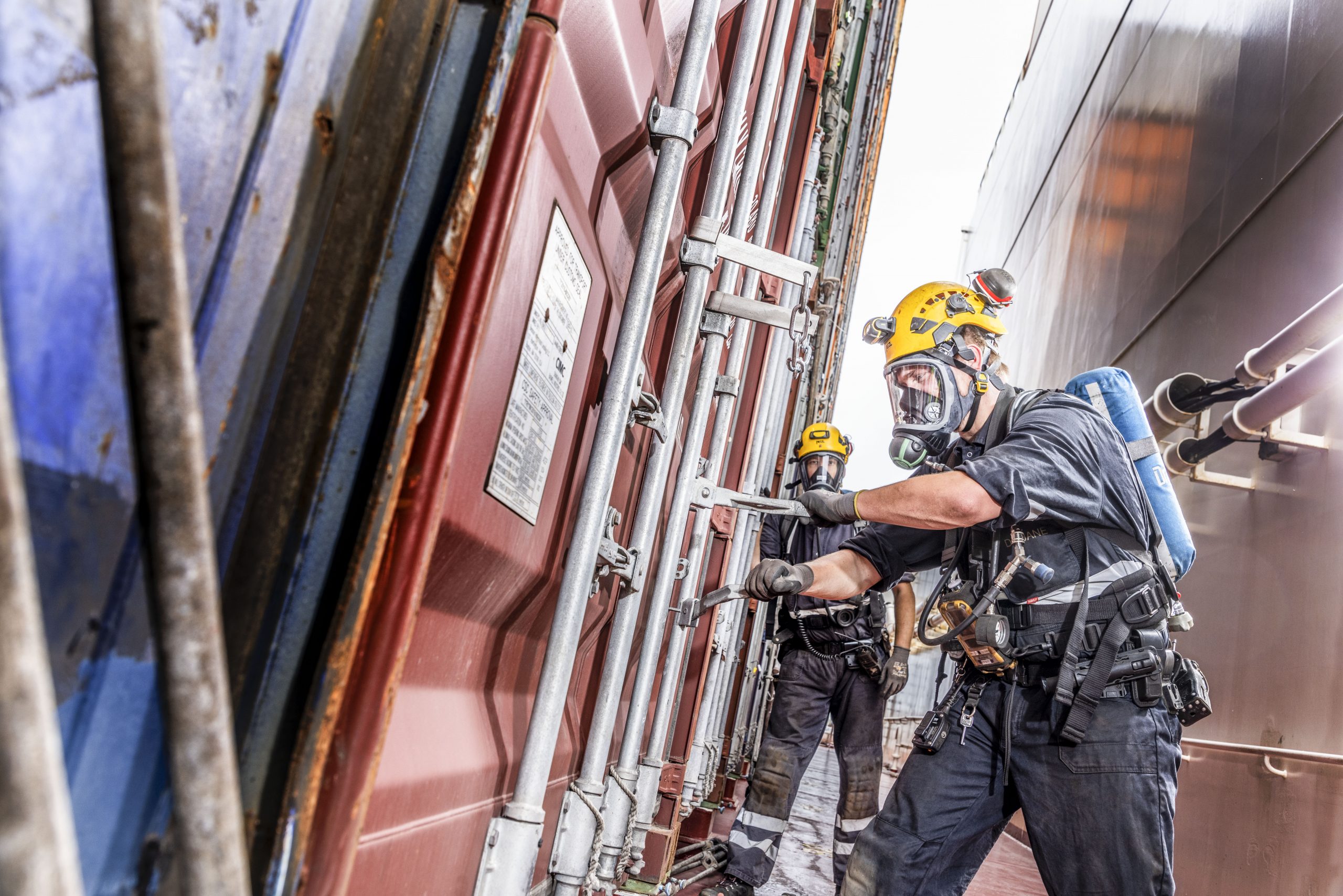 Douaniers van het Landelijk Visitatieteam maken met een gasmasker op een container open.