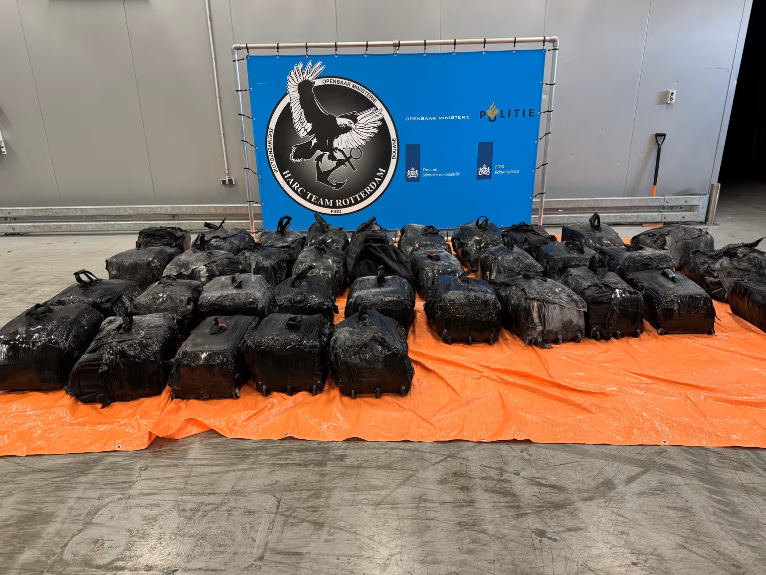 Tassen met cocaïne, opgesteld achter een banner van het HARC-team van de Douane.